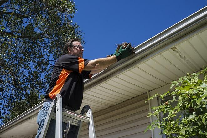 a homeowner repairing their gutter with tools in Arlington, MA