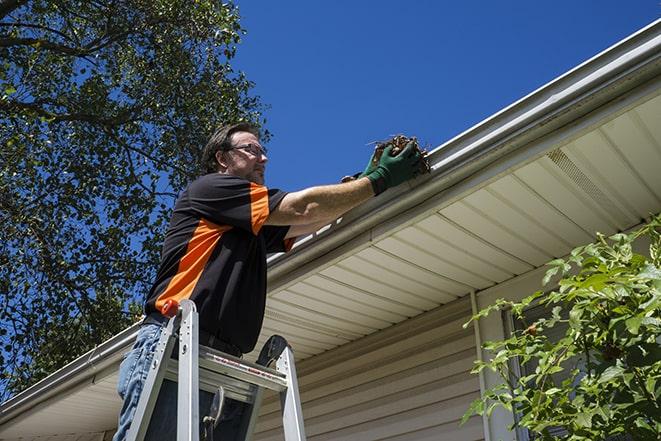 a roofer repairing a damaged gutter on a house in Boston MA